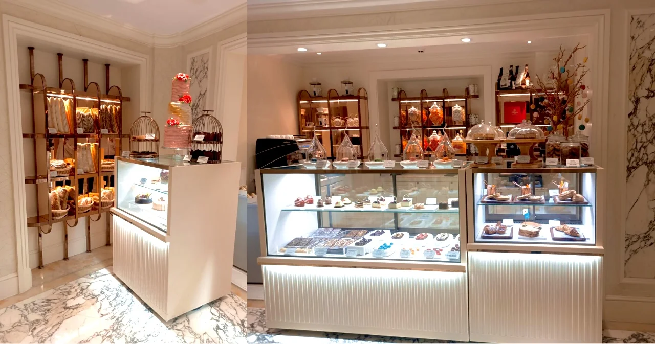 Elegant bakery display at Hilton Hotel showcasing a variety of baked goods, pastries, and cakes with a luxurious decor. Features glass display cabinets and wooden shelving for bread and confections.